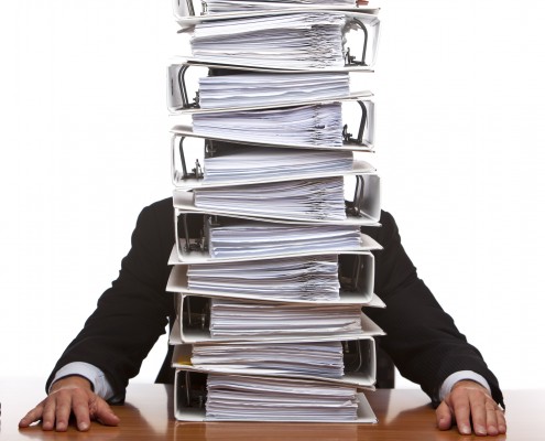 Businessman is frustrated, because of the huge documents he has to do. Isolated on white.